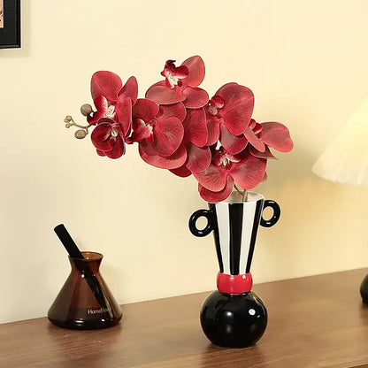 Black and white ceramic vase with red accents and handle-like ears featuring geometric stripes for living room decor