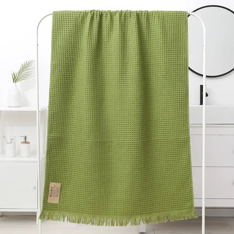 A soft olive-green decorbites geometric tassel bath towel with waffle weave and fringed edge for bathroom decor