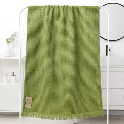 A soft olive-green decorbites geometric tassel bath towel with waffle weave and fringed edge for bathroom decor