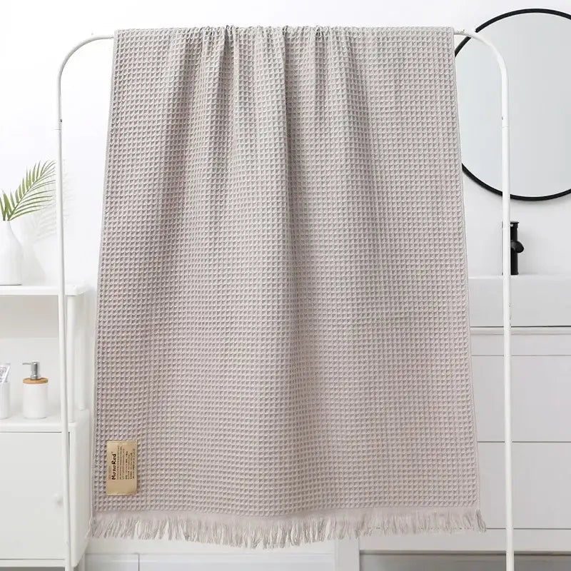 A soft light beige bath towel with waffle weave fringed edge and decorbites geometric tassel woven label corner