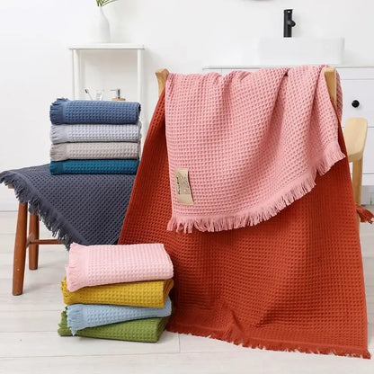 A soft pink bath towel with geometric tassel multi colored waffle weave draped over a wooden chair for decorbites geometric tassel bath decor