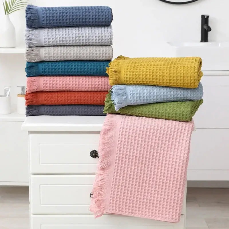 Stack of colorful multi colored geometric tassel bath towels with waffle weave and fringed edges for bathroom decor