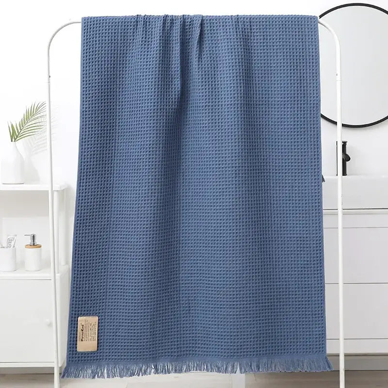 A soft blue decorbites geometric tassel bath towel with a waffle-weave textured pattern and fringed edges for bathroom decor