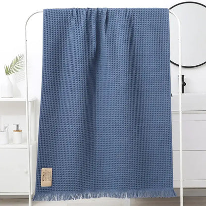 A soft blue decorbites geometric tassel bath towel with a waffle-weave textured pattern and fringed edges for bathroom decor