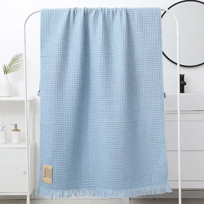 Light blue waffle weave bath towel with fringed edges and beige label for decorbites geometric tassel bath use