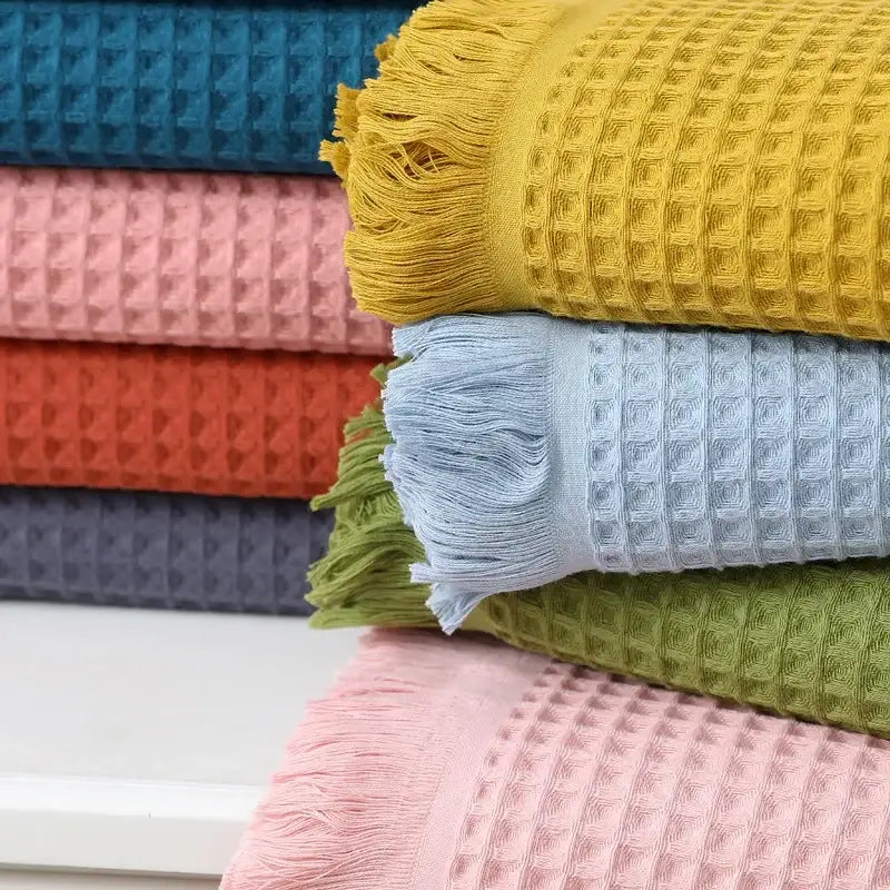 Stack of multi colored bath towels with waffle weave and fringed edges decorbites geometric tassel bath design