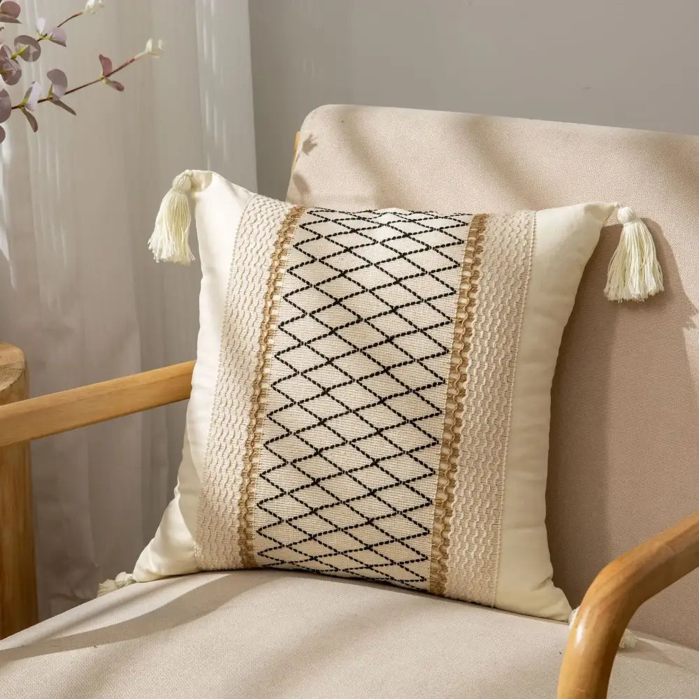 Cream-colored cushion cover with black diamond-patterned decorbites geometric tassel embroidery and beige woven trim