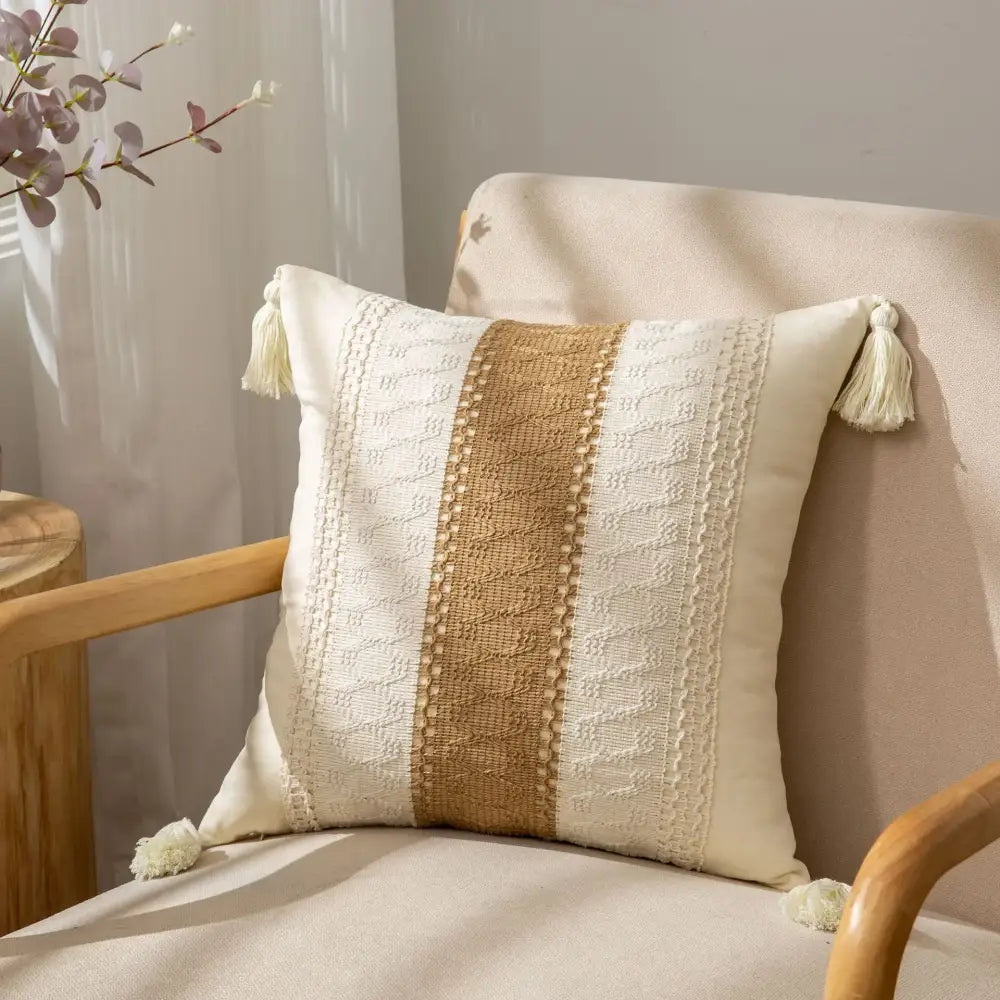 Cream-colored cushion cover with tan woven stripe and white crochet tassels for decorbites geometric tassel decor