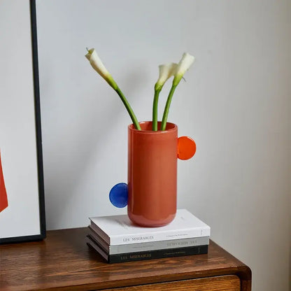 A terracotta-colored ceramic vase with blue and orange circular accents ideal for decorbites geometric glass decorbites geometric