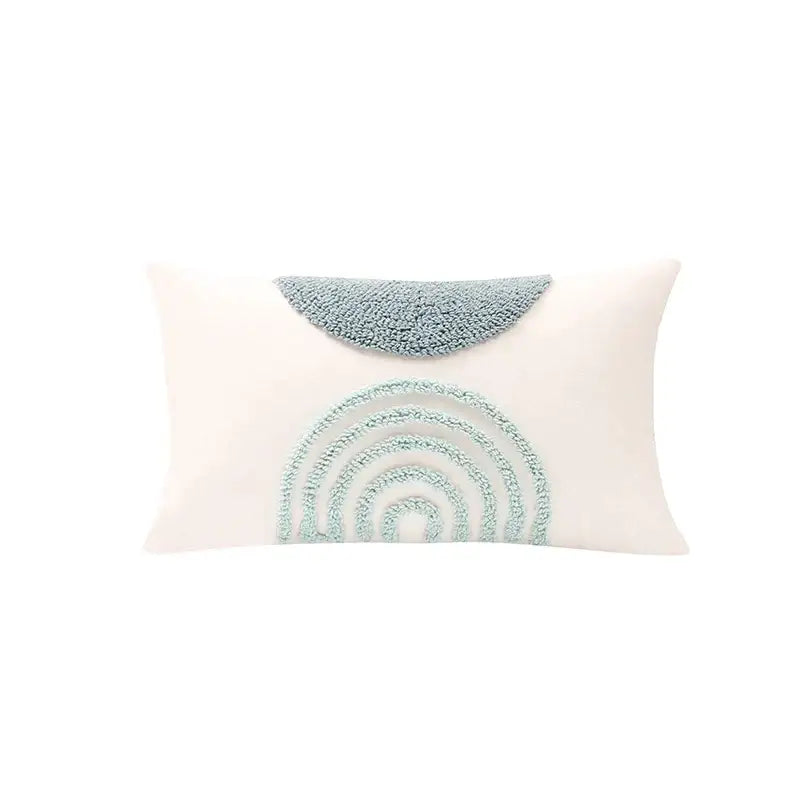 A cream-colored pillow cover with a light blue embroidered rainbow for decorbites geometric tufted diamond living room decor