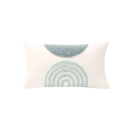 A cream-colored pillow cover with a light blue embroidered rainbow for decorbites geometric tufted diamond living room decor