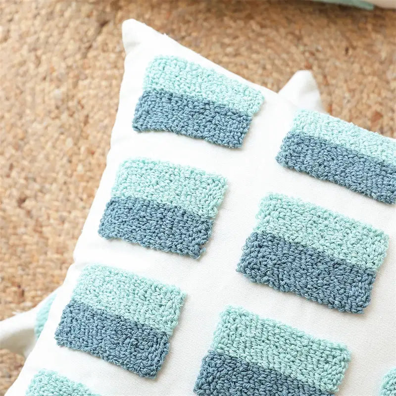 White pillow cover with decorbites geometric tufted diamond design in teal white and two-toned blue crochet squares