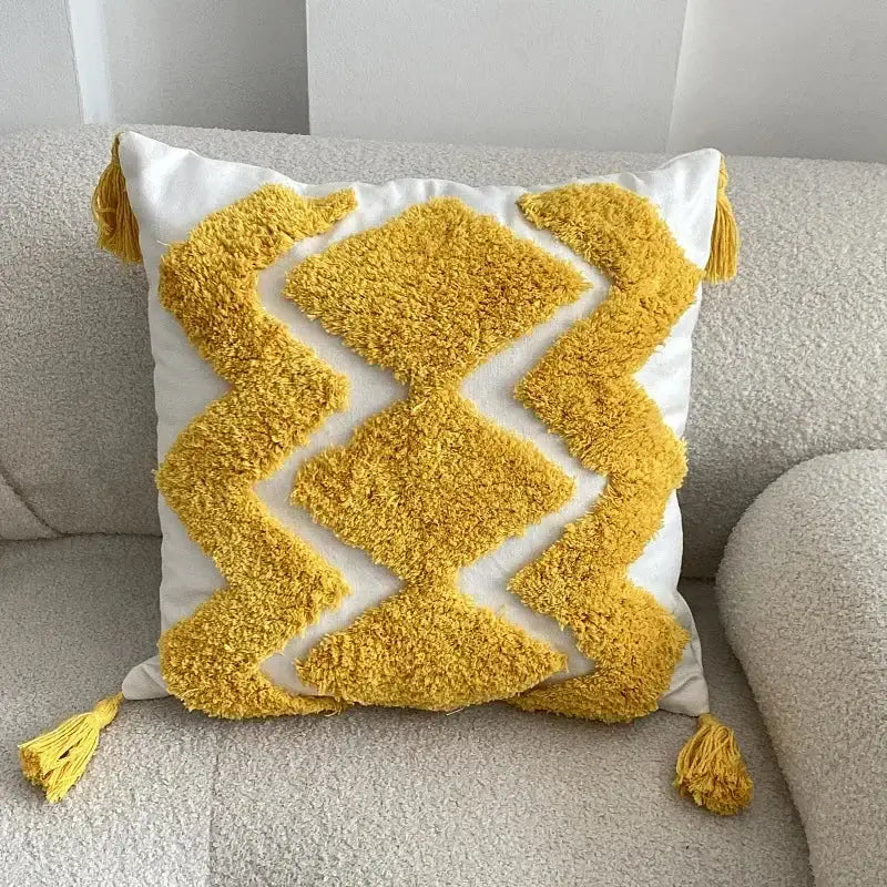 A plush geometric tufted tassel cushion cover with a white base yellow diamond pattern and matching corner tassels