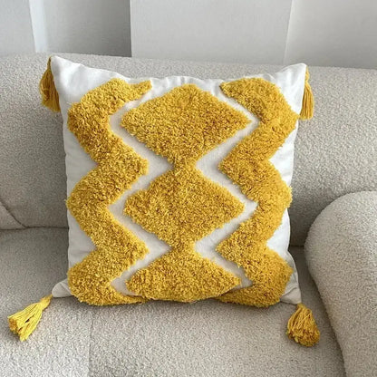 A plush geometric tufted tassel cushion cover with a white base yellow diamond pattern and matching corner tassels