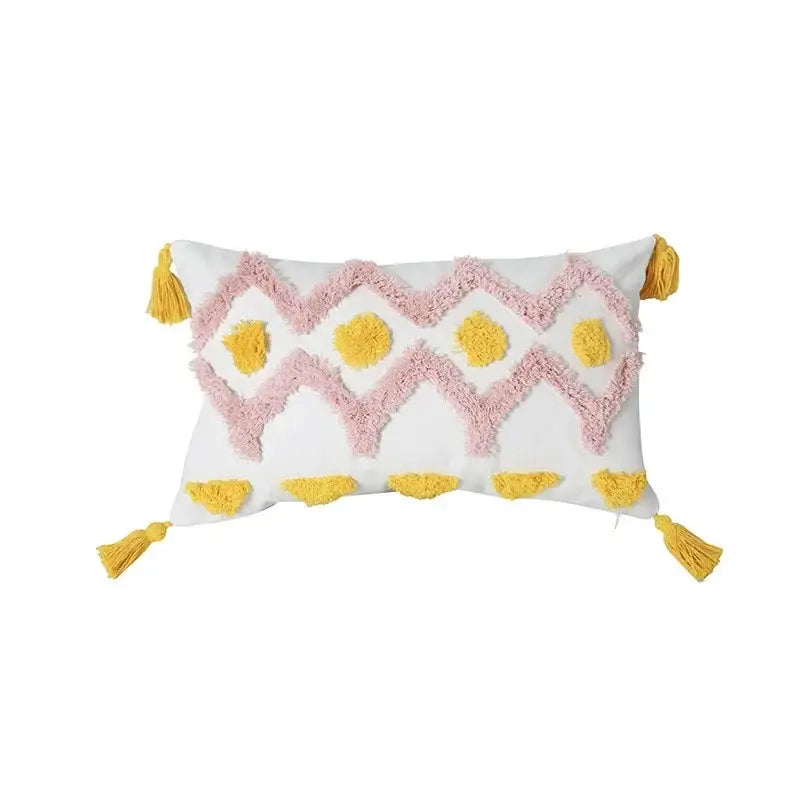 A white rectangular geometric tufted tassel cushion cover with pink and yellow pattern and tassels on each corner