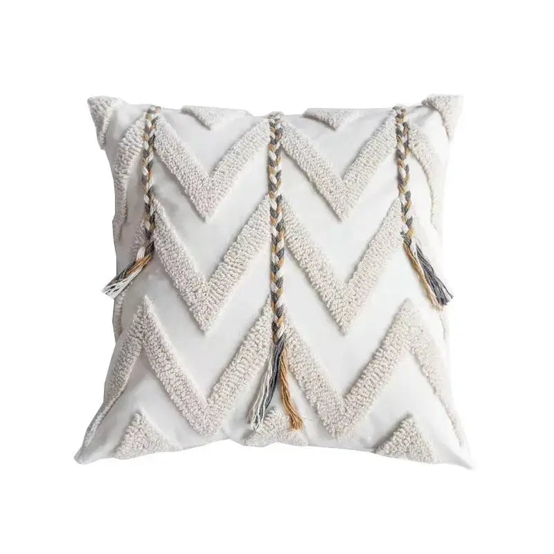 Square white cushion cover with geometric tufted tassel pattern and three braided tassels in beige and gray tones