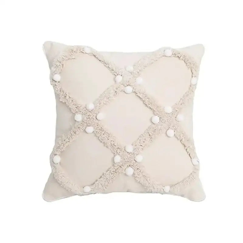 Cream-colored cushion cover with geometric tufted tassel pattern and white pom-poms for beige and gray decor
