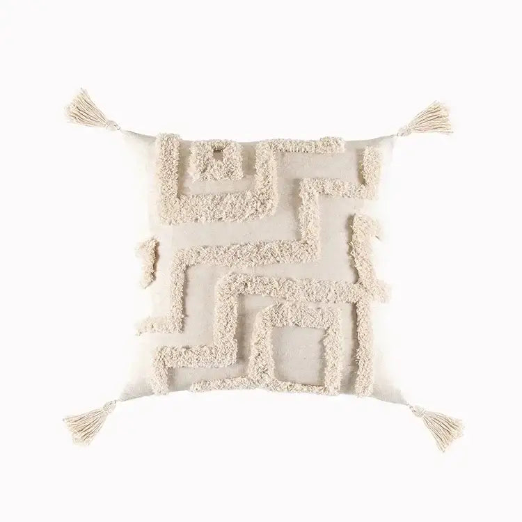 Cream-colored cushion cover with geometric tufted tassel detailing and tassels at each corner for living room decor