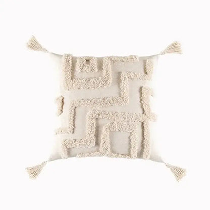 Cream-colored cushion cover with geometric tufted tassel detailing and tassels at each corner for living room decor