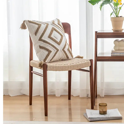 Cream-colored cushion cover with geometric gold embroidery and tufted tassel detailing for beige and gray decor