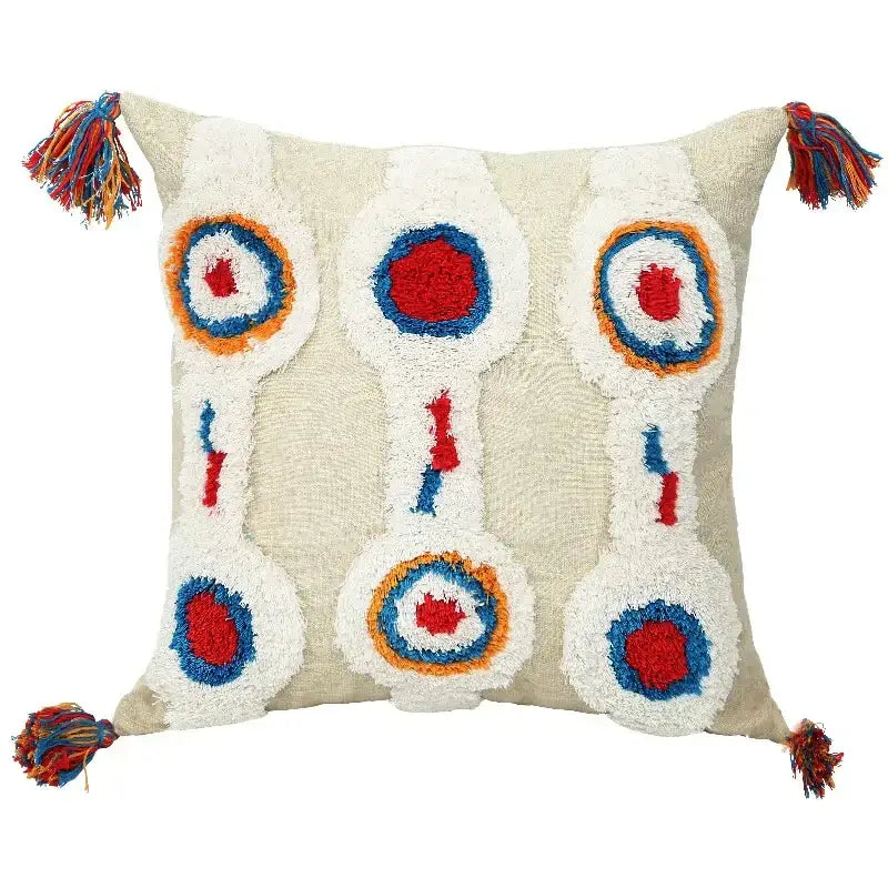 Beige cushion cover with geometric tufted tassel design featuring colorful embroidered circles and multicolored tassels