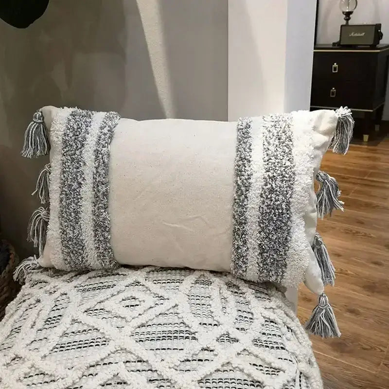 Cream-colored cushion cover with textured gray and white woven stripes and decorative tassels for decorbites geometric tufted tassel decor