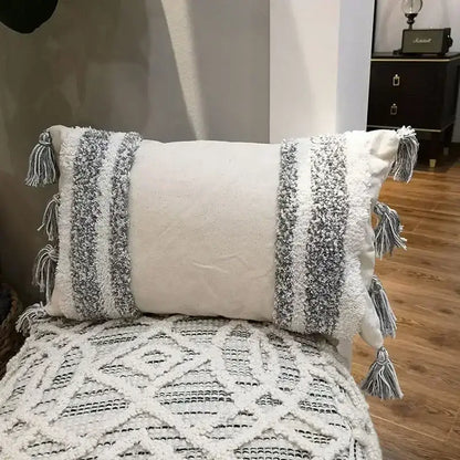 Cream-colored cushion cover with textured gray and white woven stripes and decorative tassels for decorbites geometric tufted tassel decor
