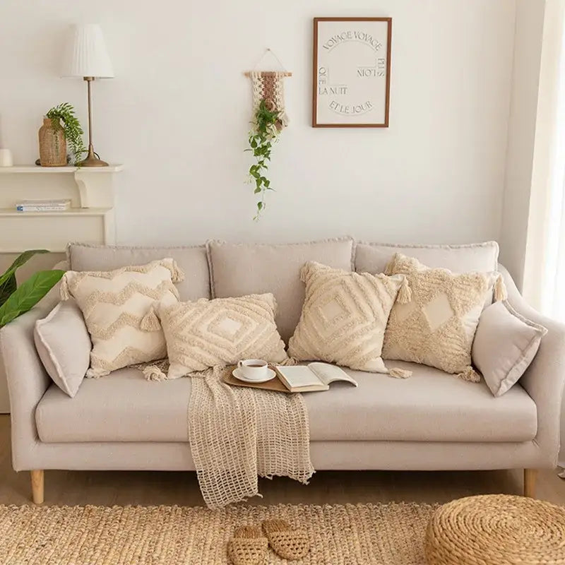 Beige upholstered sofa with decorbites geometric tufted tassel pillowcases in cotton linen and a woven blanket draped