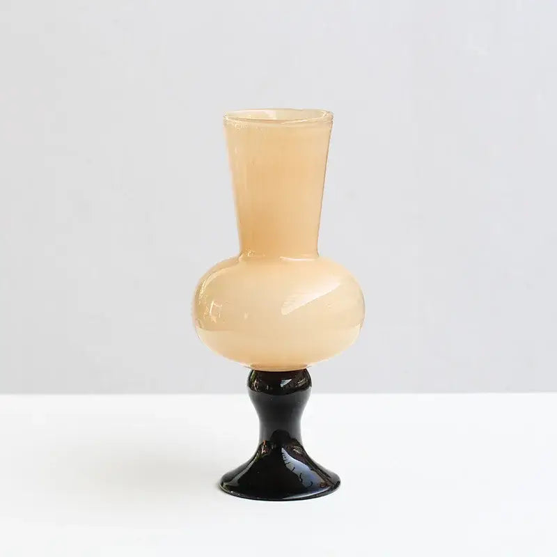 A sleek translucent peach geometric vintage glass vase with a glossy black pedestal base for living room decor