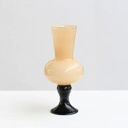 A sleek translucent peach geometric vintage glass vase with a glossy black pedestal base for living room decor