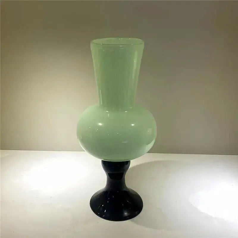 A sleek translucent light green geometric vintage glass vase on a black glossy pedestal base for decorbites geometric vintage decor