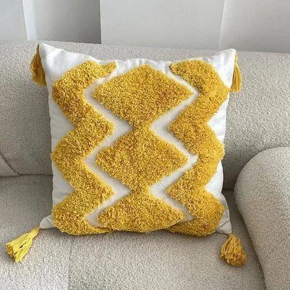 A plush white pillow cover with bold yellow geometric waves tufted in textured yarn and matching tassels for decorbites geometric waves