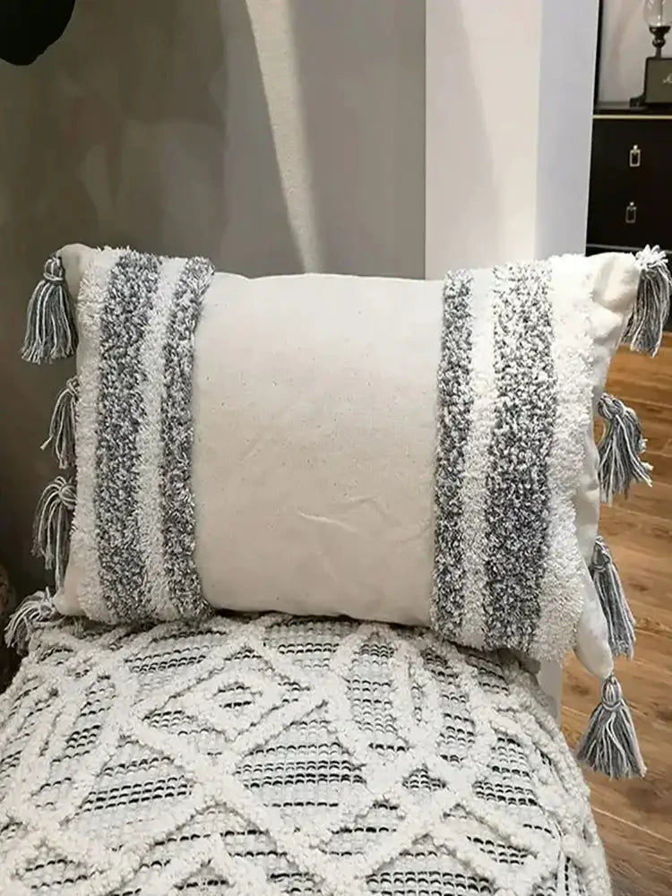 A cozy off-white geometric waves tufted pillow cover with textured gray and white woven stripes and fringe tassels