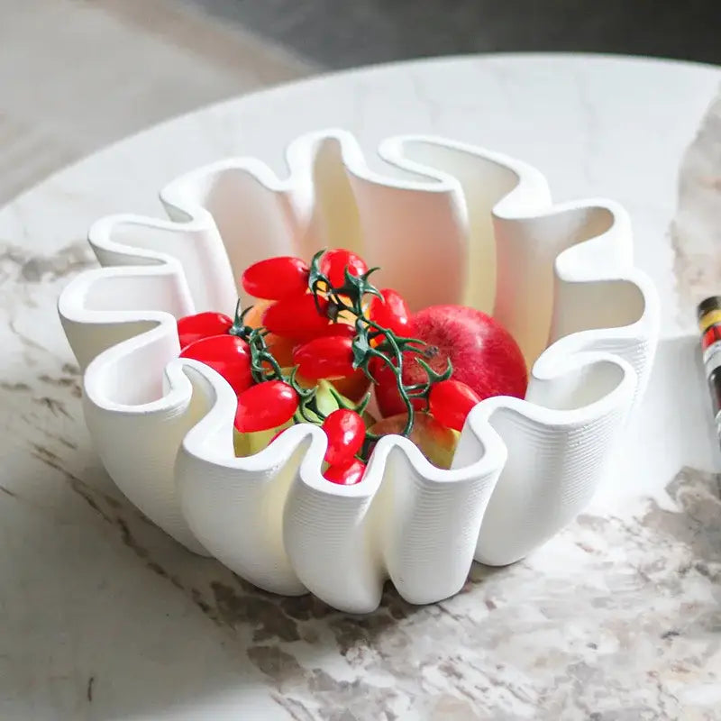 White sculpted ceramic fruit plate tray with wavy petal edges holding cherry tomatoes and an apple for kitchen storage