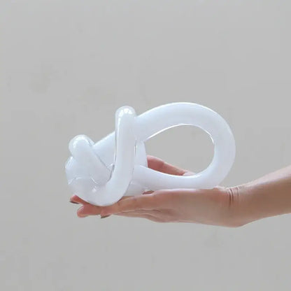 A translucent white glass twine knot sculpture with a smooth glossy finish for home decor by decorbites geometric glass