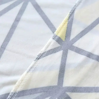 A soft white decorbites geometric stretch sofa cover with gray intersecting lines and yellow accents for couch protection