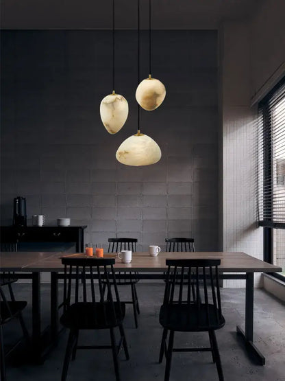 Three creamy white marble pendant lights with organic shades hang from black cords in decorbites geometry marble led chandelier
