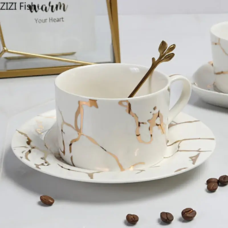 White ceramic cup and saucer with gilded marble texture and golden leaf spoon decorbites gilded marble luxury set