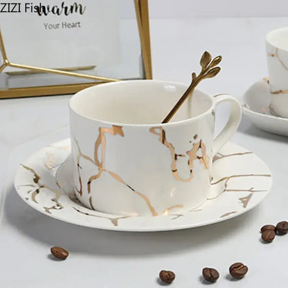 White ceramic cup and saucer with gilded marble texture and golden leaf spoon decorbites gilded marble luxury set