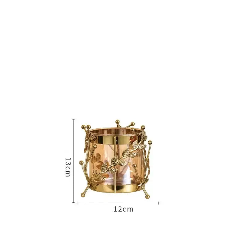 Gold-toned metal candle holder with intricate gilded tree branch detailing and clear glass center for living room display