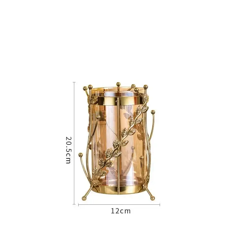 Golden metal gilded tree branch candle holder with intricate leaf and vine detailing and clear glass cylinder vase