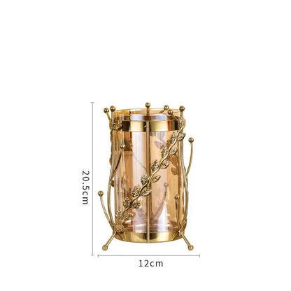 Golden metal gilded tree branch candle holder with intricate leaf and vine detailing and clear glass cylinder vase