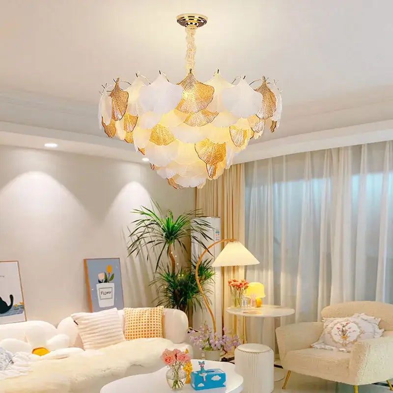 A dimmable white and gold leaf-shaped ginkgo chandelier suspended from a golden fixture for dining room decorbites ginkgo art