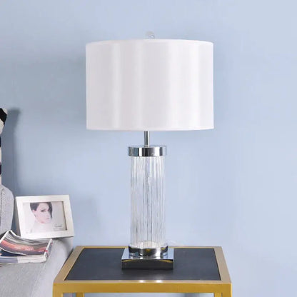Clear glass crystal cylinder table lamp with vertical ridges chrome accents and cream drum shade for bedroom use