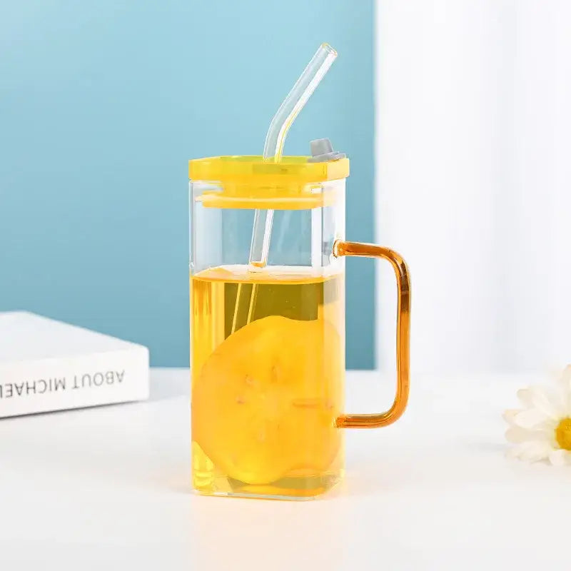 Clear glass drinking cup with yellow lid and handle filled with orange liquid by decorbites glass drinking cups