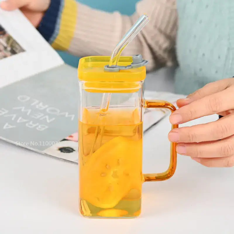 Clear glass drinking cup with yellow lid amber handle and straw filled with orange liquid and fruit slices decorbites glass drinking cups