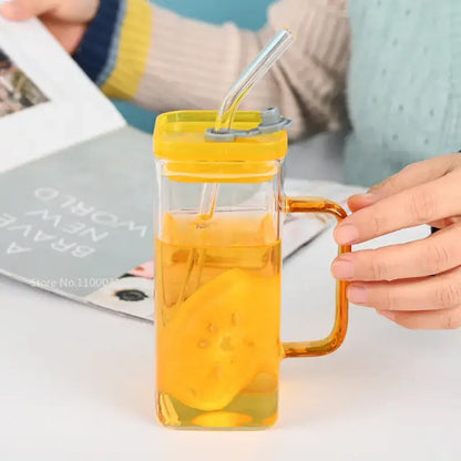Clear glass drinking cup with yellow lid amber handle and straw filled with orange liquid and fruit slices decorbites glass drinking cups