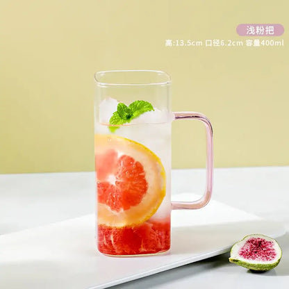 A clear glass drinking cup with a pink handle filled with ice and citrus slices from decorbites glass drinking cups