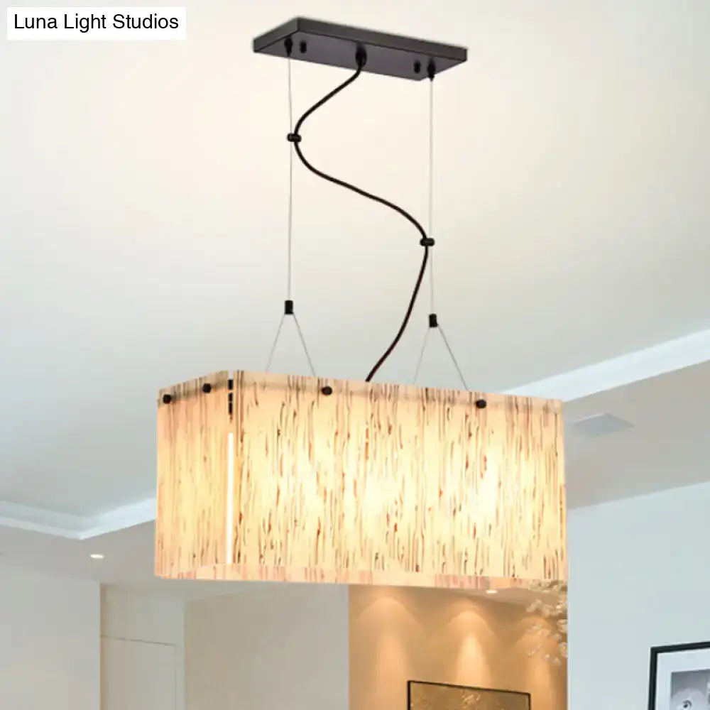 Rectangular pendant light with warm textured wood finish and black metal hardware for beige glass island dining lighting
