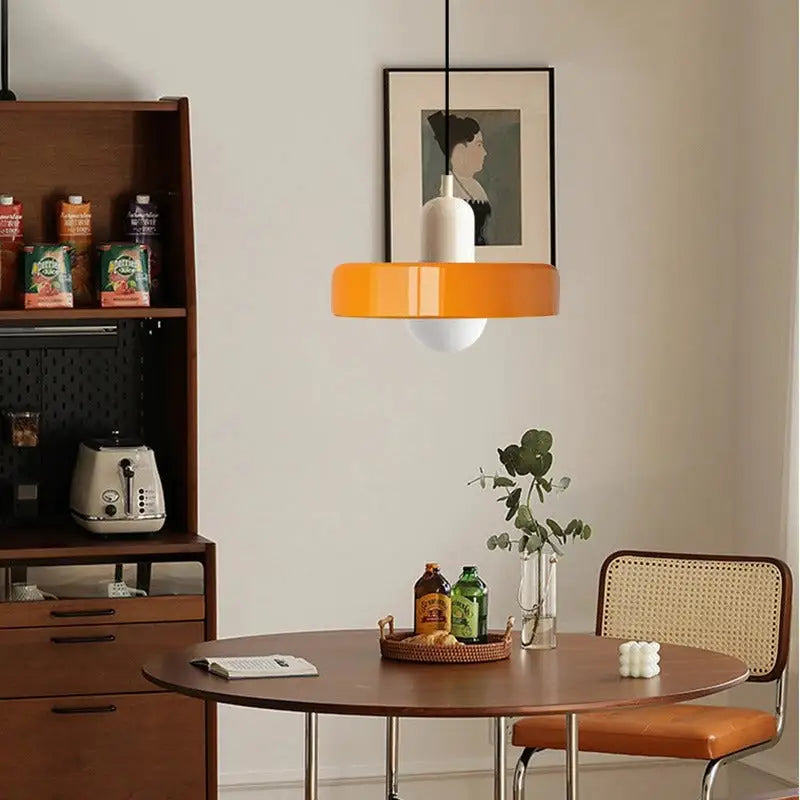 Modern glass pendant lighting with vibrant orange circular glass shade and white cylindrical base suspended by black cord